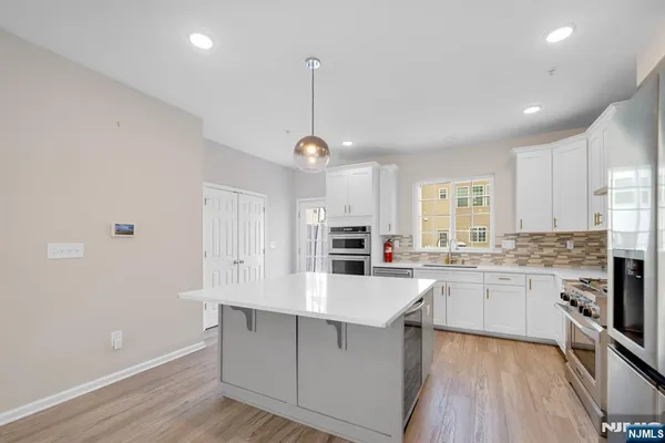 a large kitchen with kitchen island a sink a center island stainless steel appliances and a window