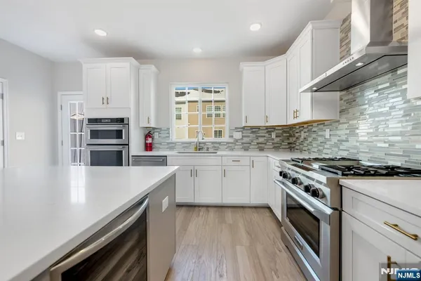 a kitchen with stainless steel appliances white cabinets and a stove top oven