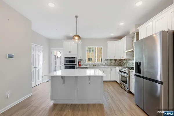 a large kitchen with cabinets wooden floor and stainless steel appliances