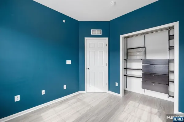 a view of an empty room with closet and wooden door