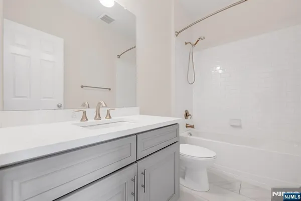 a bathroom with a granite countertop sink a toilet and shower