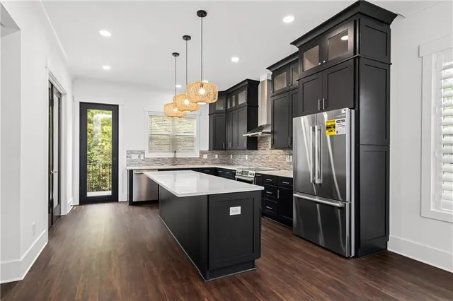 a kitchen with stainless steel appliances granite countertop a refrigerator a sink dishwasher a stove and white countertops with wooden floor