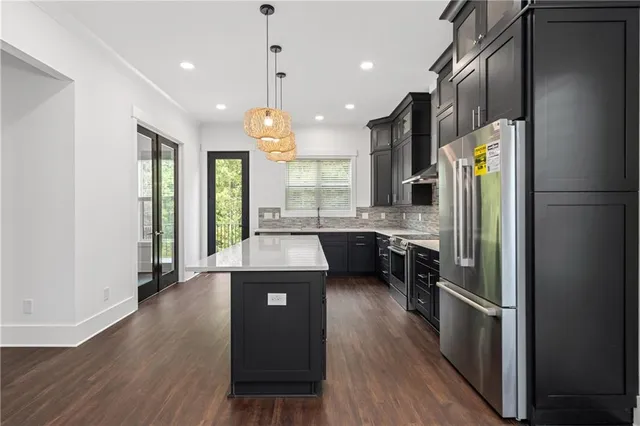 a kitchen with granite countertop a stove a sink a refrigerator and a wooden floor