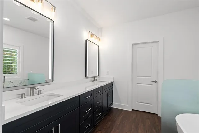 a spacious bathroom with a double vanity sink a mirror and a bathtub