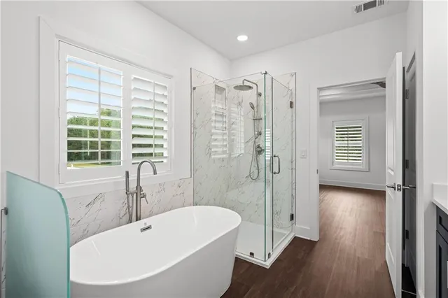 a spacious bathroom with a double vanity sink a large mirror a bathtub and shower