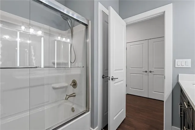 an empty room with wooden floor chandelier fan and windows