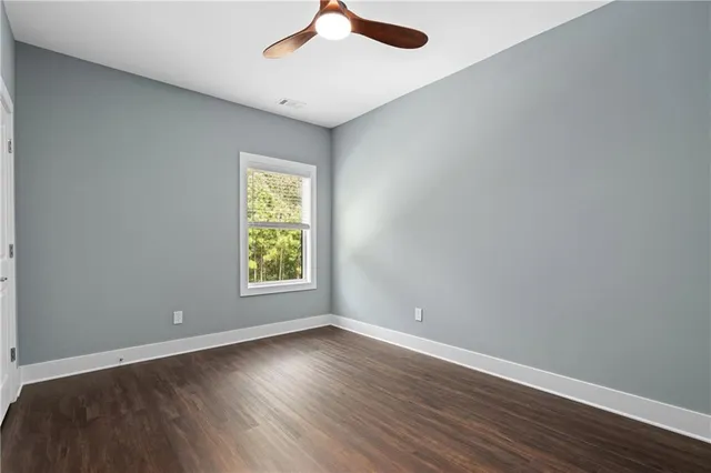 an empty room with wooden floor chandelier fan and windows