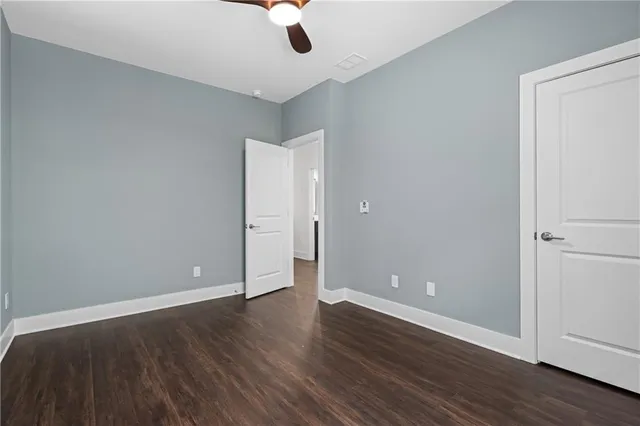 an empty room with wooden floor closet and windows