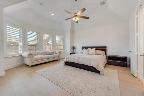 a spacious bedroom with a bed a couch and a large window