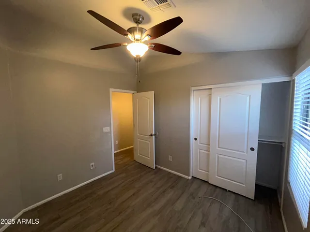 an empty room with wooden floor and a ceiling fan