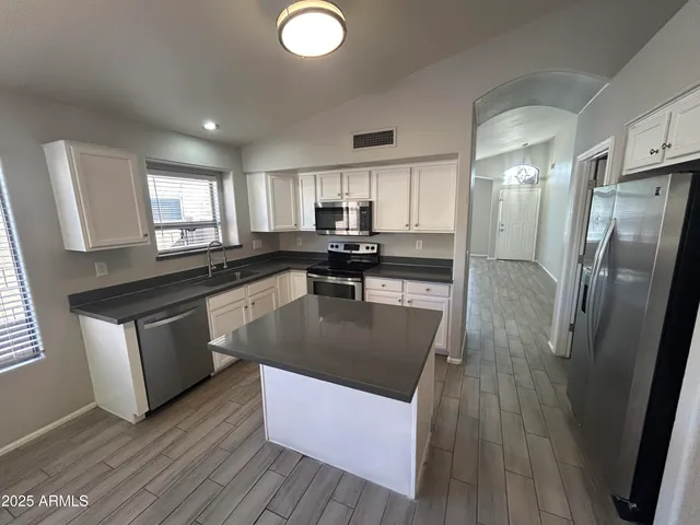 a kitchen with stainless steel appliances granite countertop a sink a stove a refrigerator and island