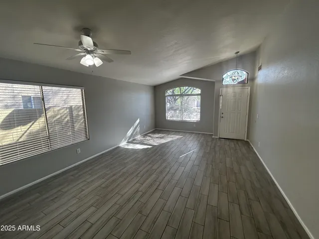a view of an empty room with wooden floor and a window