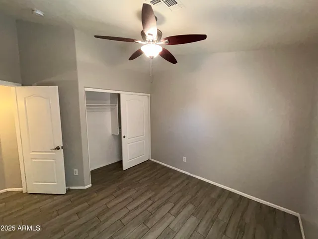 a view of a room with wooden floor and a ceiling fan