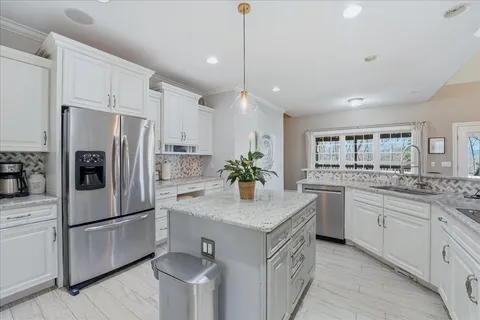 a kitchen with stainless steel appliances granite countertop a potted plant on the granite counter tops and a window