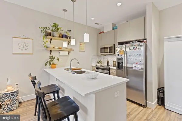 a kitchen with stainless steel appliances a refrigerator a sink a stove a dining table and chairs