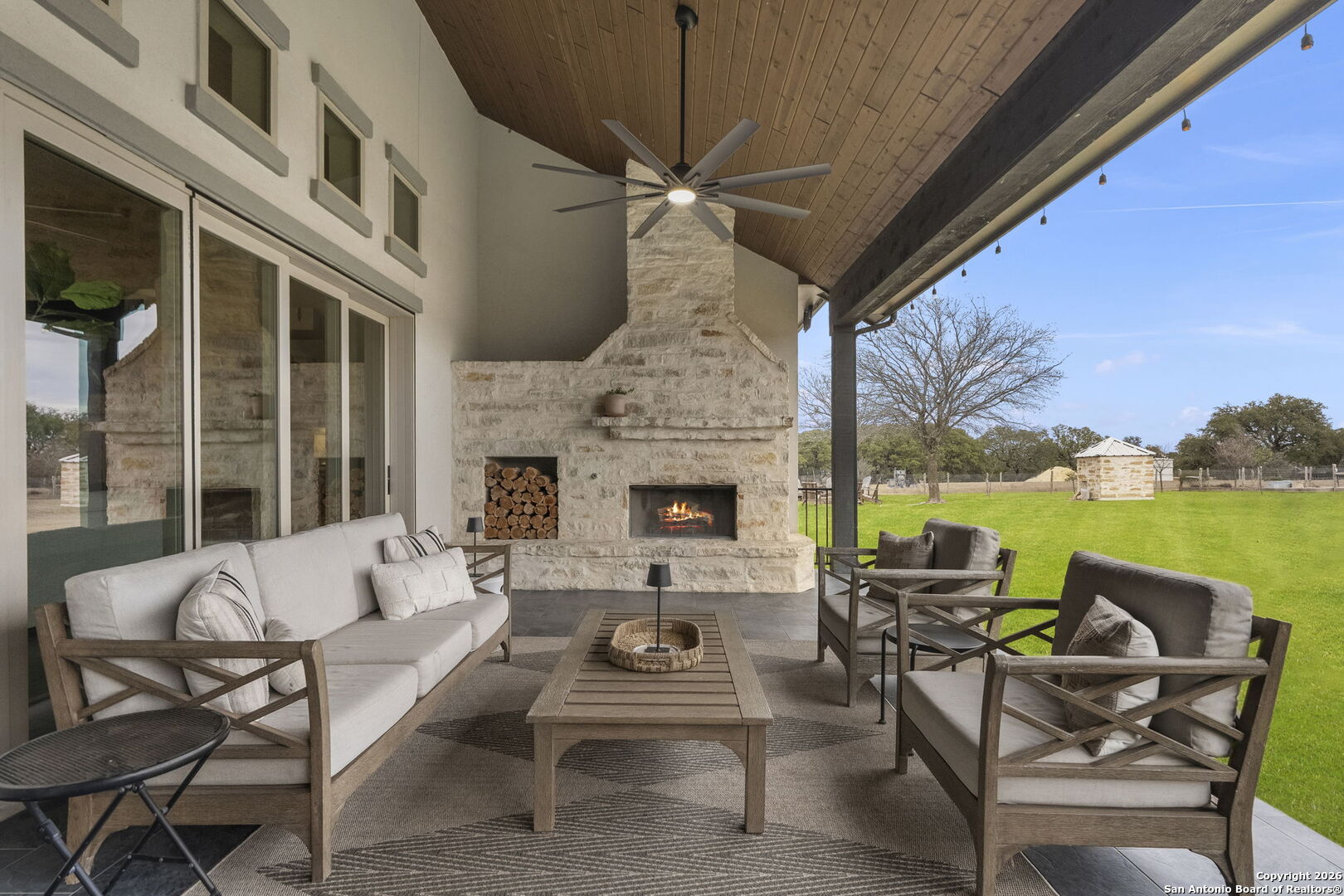 71 Sabinas Creek Ranch Road Boerne, TX 78006 - Photo 29 of 38 a view of a patio with couches table and chairs under an umbrella with a fire pit