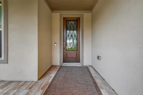 a view of a hallway with wooden floor and a bathroom