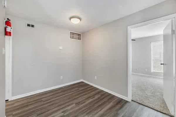 a view of an empty room with wooden floor and closet