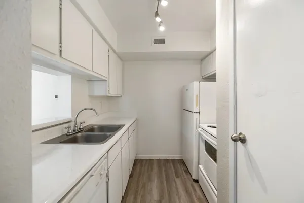 a kitchen that has a sink a refrigerator and cabinets