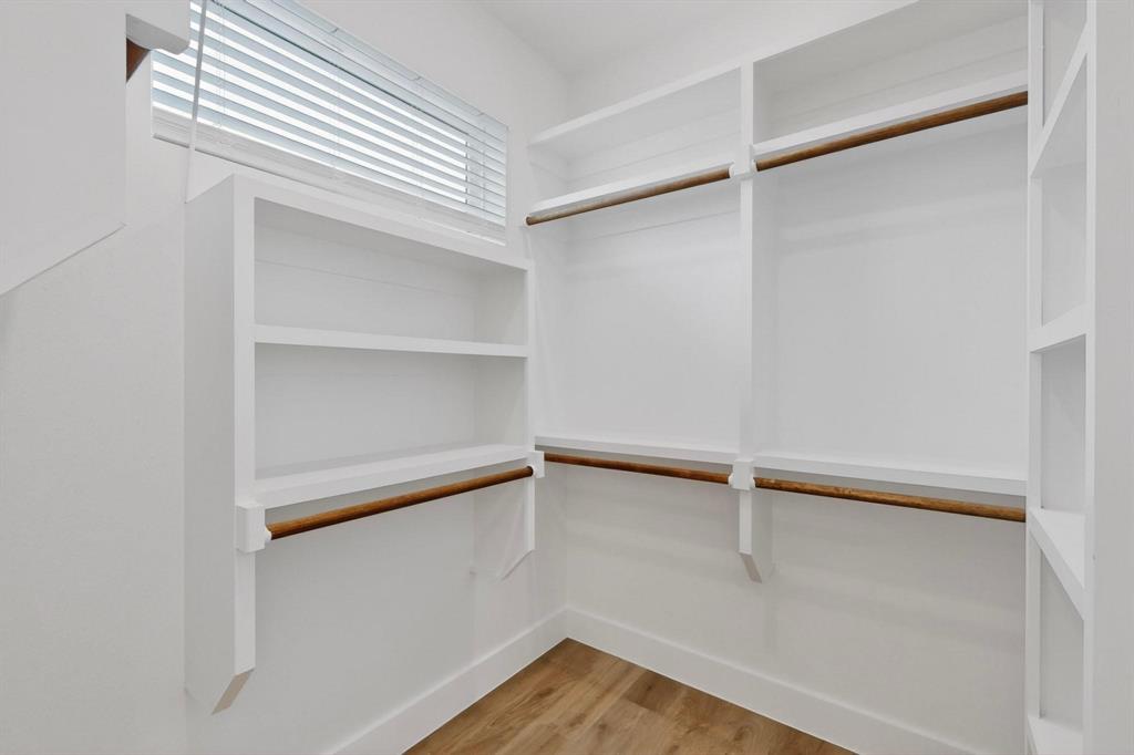 2226 Shea Road, Unit 103 Dallas, TX 75235 - Photo 19 of 35 Walk-in closet featuring white built-in shelving, multiple hanging rods, and wood-finish flooring