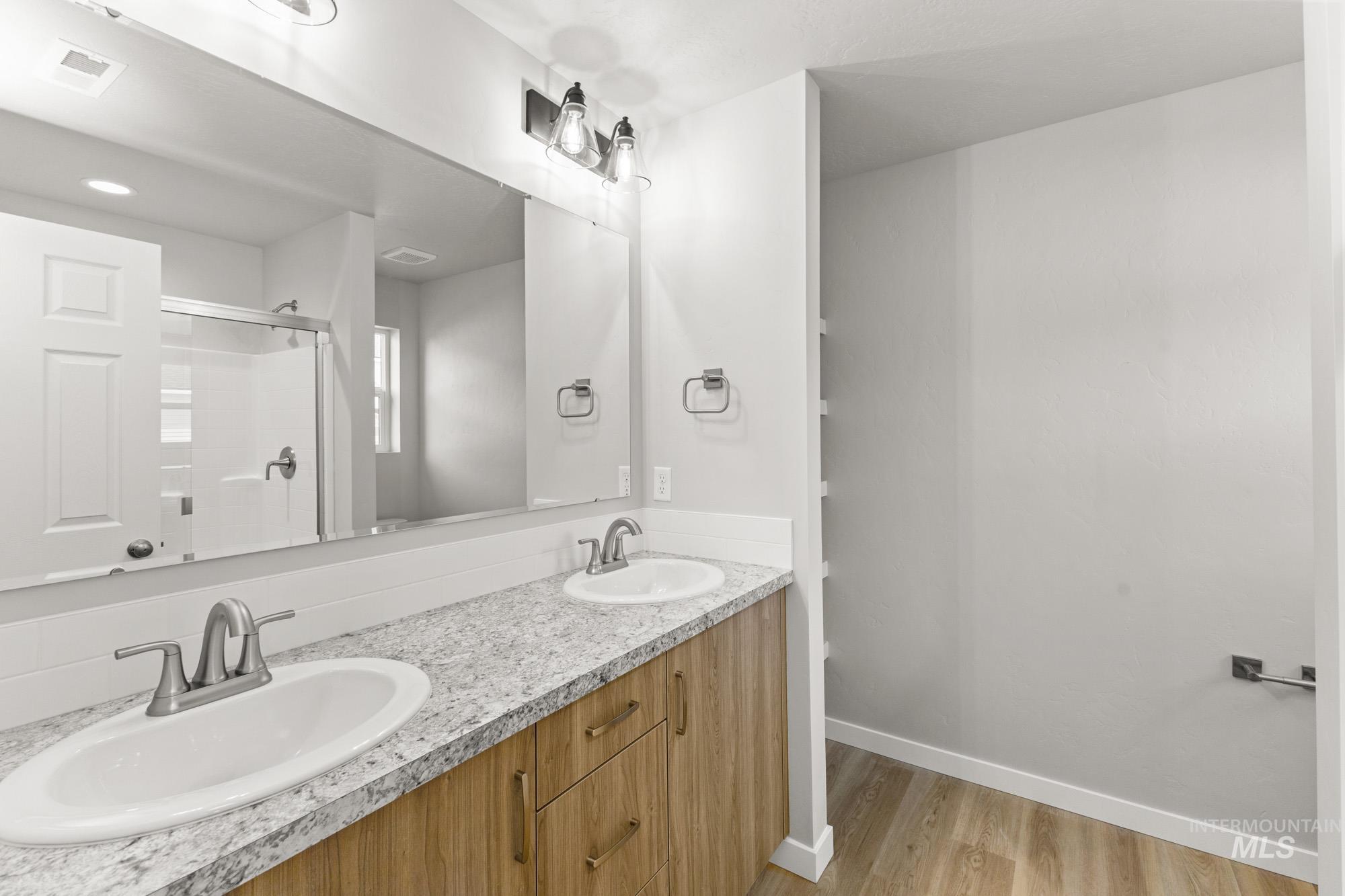 436 Merlin Court Middleton, ID 83644 - Photo 19 of 20 Double vanity featuring two undermount sinks, speckled countertops, and wood-finish cabinetry