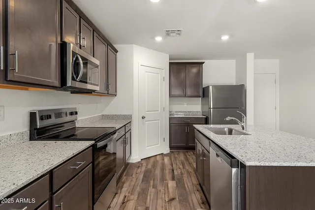 a kitchen with stainless steel appliances granite countertop a sink stove and refrigerator