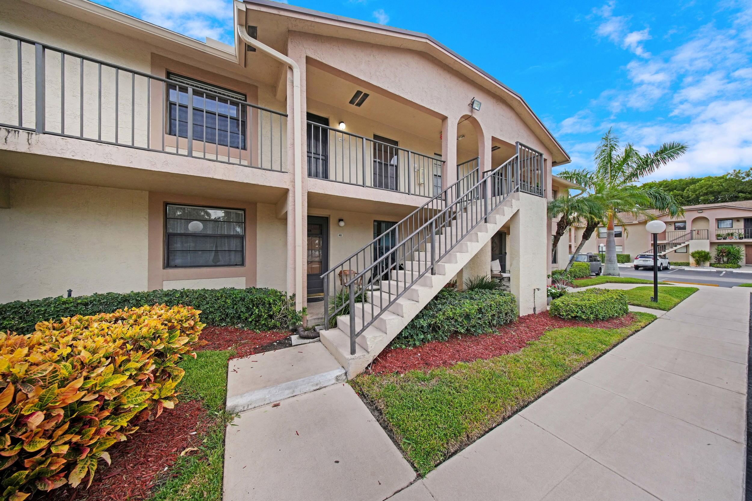 9480 Boca Cove Circle, Unit 415 Boca Raton, FL 33428 - Photo 2 of 25 a front view of a house with a yard and potted plants