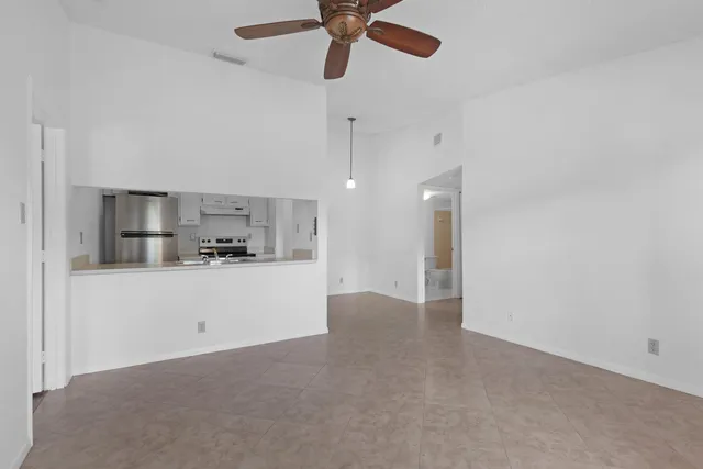 a view of a kitchen with a sink and dishwasher a refrigerator freezer a stove with white cabinets