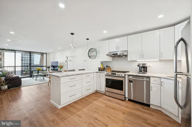 a kitchen with stainless steel appliances granite countertop a stove a sink dishwasher and a refrigerator with wooden floor