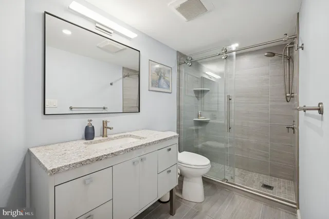 a bathroom with a granite countertop sink toilet mirror and shower