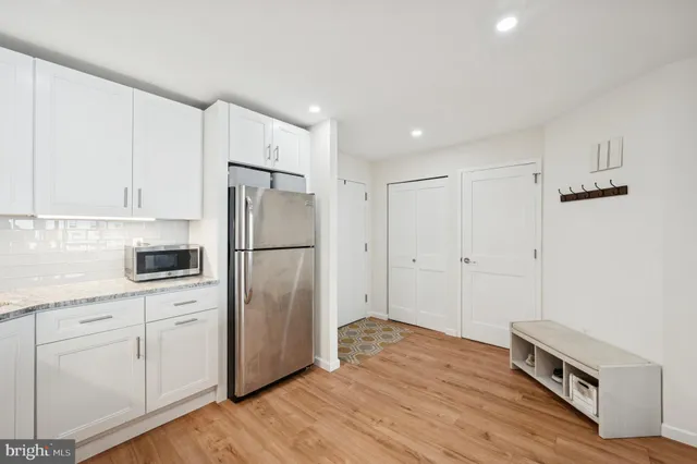 a kitchen with a refrigerator a stove and white cabinets