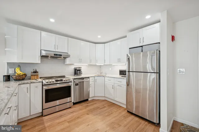 a kitchen with stainless steel appliances granite countertop a refrigerator a stove a sink and white cabinets