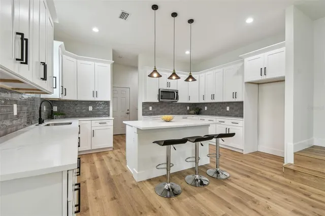 a kitchen with stainless steel appliances kitchen island granite countertop a sink a stove and a refrigerator