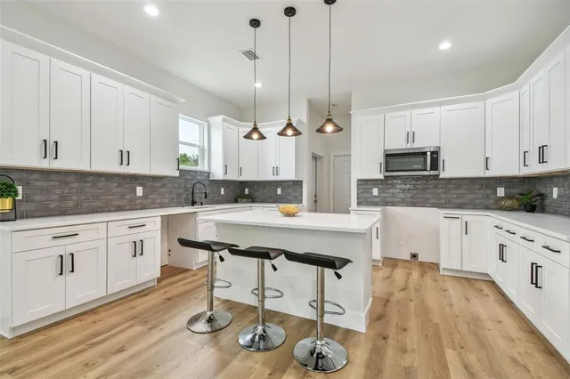 a kitchen with stainless steel appliances granite countertop a stove a sink and white cabinets with wooden floor