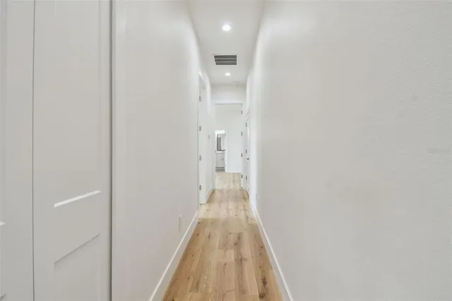 a view of a hallway with wooden floor and a bathroom