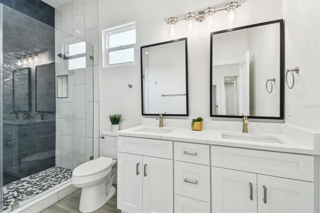 a bathroom with a double vanity sink toilet and shower