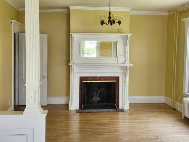 a view of a livingroom with wooden floor and a fireplace