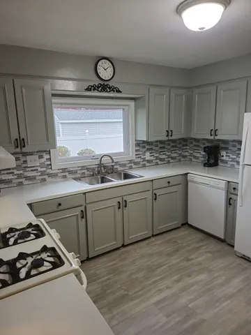 a kitchen with a stove white cabinets sink and dishwasher