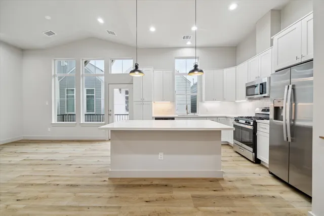 a large kitchen with a large counter top stainless steel appliances and a ceiling fan