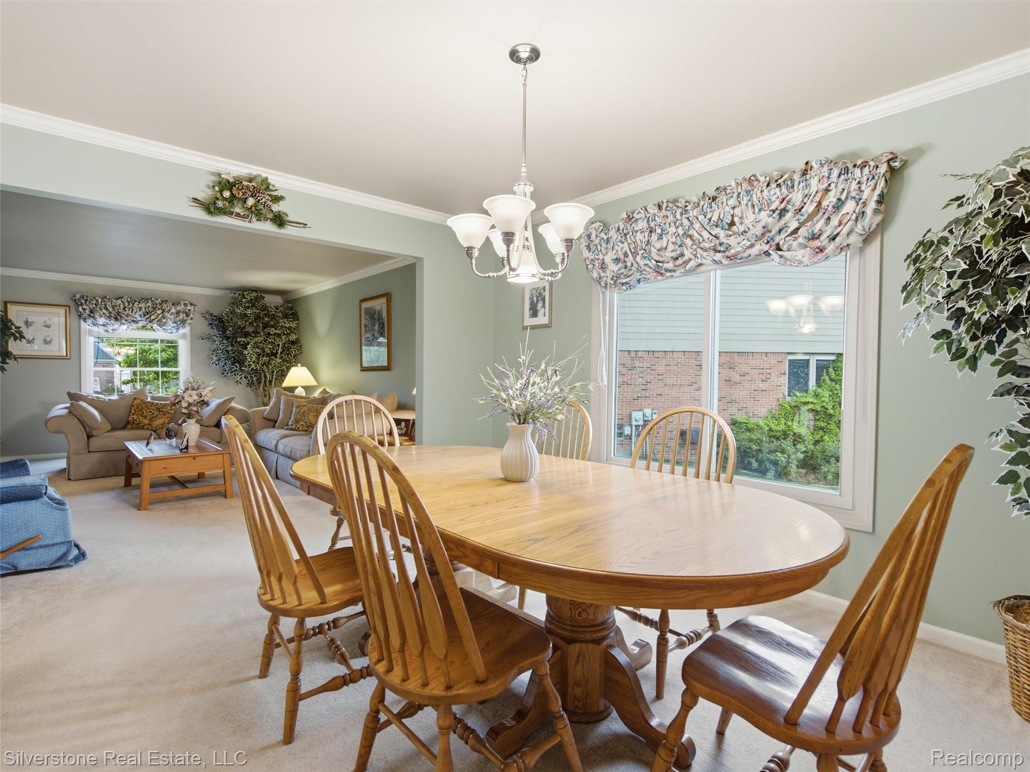 6577 Edith Court Troy, MI 48085 - Photo 19 of 61 Dining area featuring a wood-finish oval table and matching chairs, white window trim, crown molding, and a chandelier with frosted glass shades