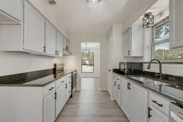 a kitchen with granite countertop a sink and cabinets