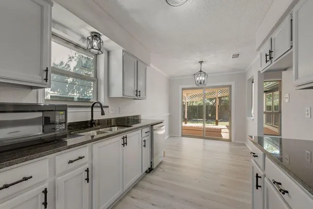 a kitchen with granite countertop a sink a counter space appliances and cabinets