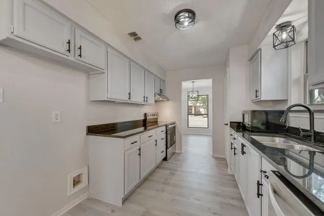 a kitchen with granite countertop a sink stove and cabinets