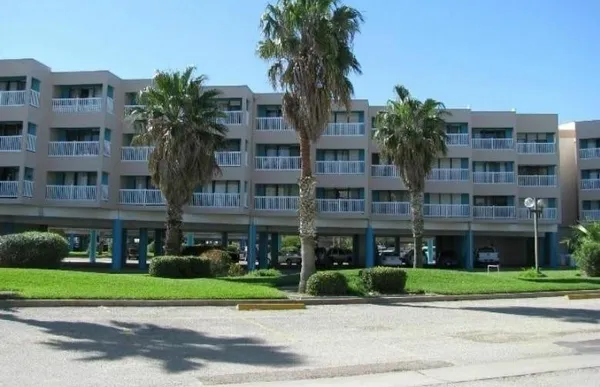 a front view of multi story residential apartment building with yard and traffic signal