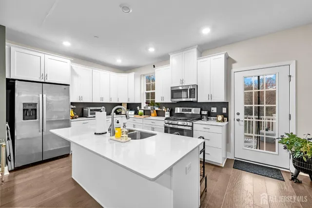 a kitchen with stainless steel appliances kitchen island granite countertop a refrigerator and a stove top oven