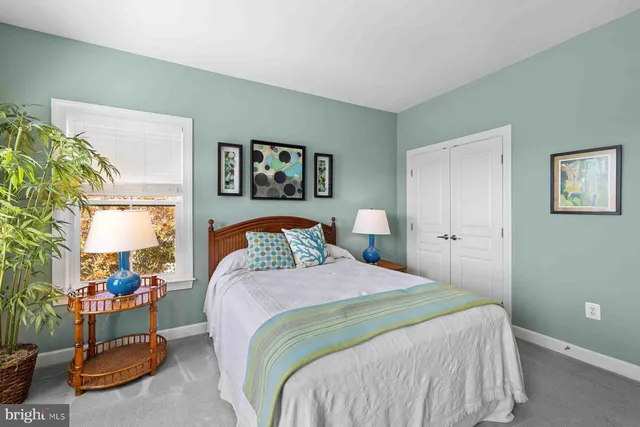 a bedroom with a bed a mirror on dresser and a window