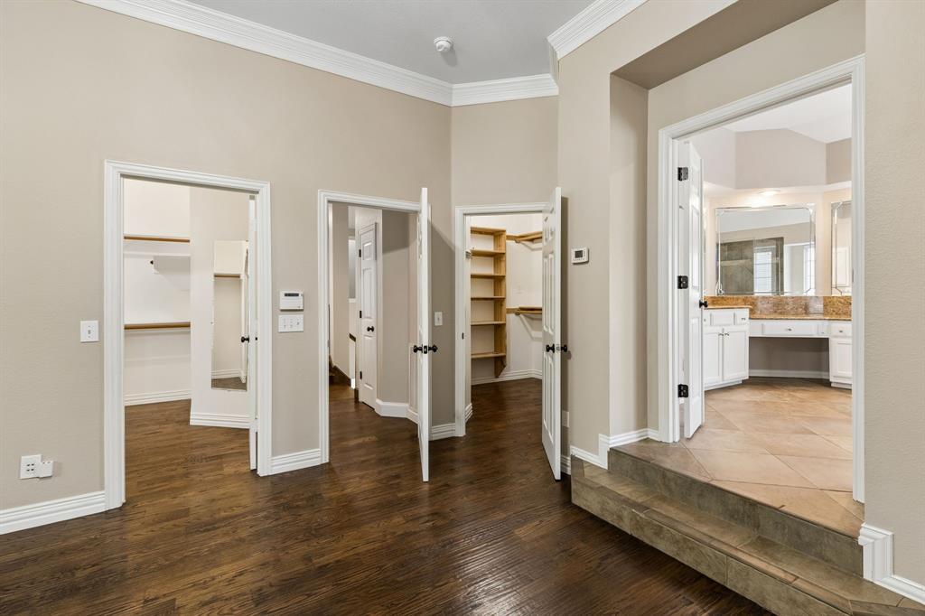 2925 Sunset Ridge McKinney, TX 75072 - Photo 22 of 33 Luxurious primary suite offering exceptional scale, rich hardwood flooring, and a private elevated entry leading into the spa-inspired ensuite bath and 2 expansive custom closets.