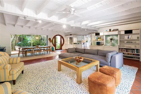 a living room with furniture a rug kitchen view and a large window