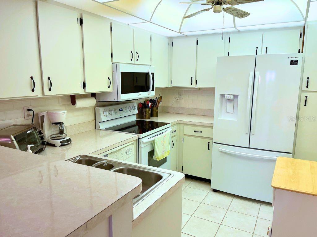 3006 Caring Way, Unit 329 Port Charlotte, FL 33952 - Photo 8 of 37 a kitchen that has a lot of white cabinets and stainless steel appliances