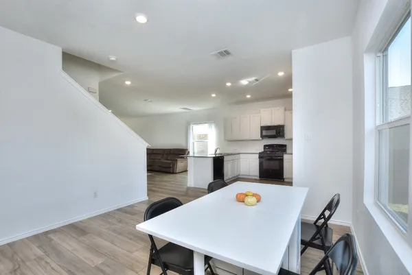 a kitchen with a table chairs a refrigerator and a stove